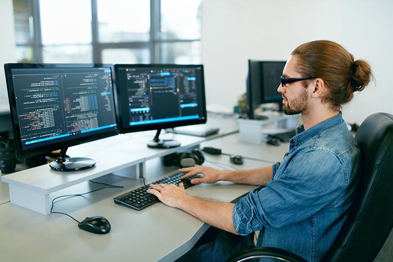 编程. 在IT办公室工作的人，坐在办公桌前写代码. Programmer Typing Data Code, Working On Project In Software Development 公司. 高质量图像.